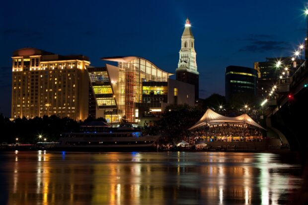 The Hartford skyline at night with illuminated buildings and calm river reflections