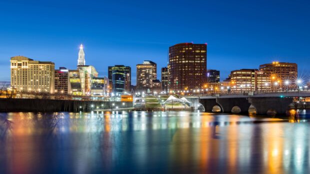 Hartford skyline at night with illuminated buildings reflecting on the water