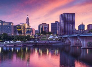 Hartford skyline with a vibrant sunset reflecting on the river and city buildings