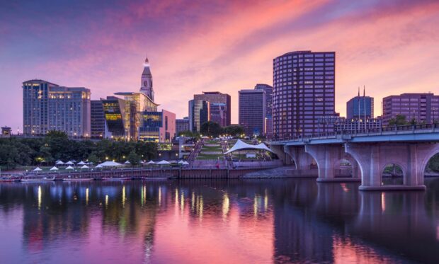 Hartford skyline with a vibrant sunset reflecting on the river and city buildings