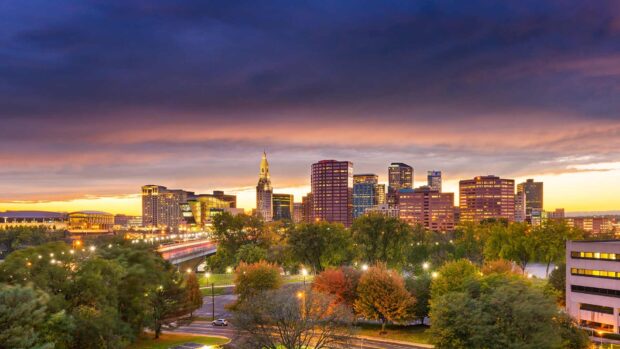 Hartford skyline showcasing autumn trees and city buildings at sunset with colorful sky
