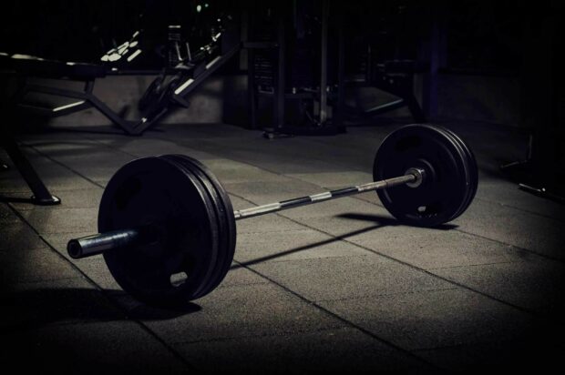 A heavy barbell set is positioned on the gym floor for powerlifting training, 2K Desktop Wallpaper