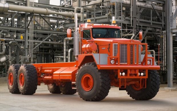 A heavy duty Kenworth truck chassis is displayed in an industrial area with complex piping, HD Desktop Wallpaper