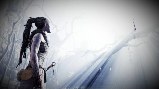 A Hellblade character stands in a foggy forest with light shining through barren trees, 4K Desktop Wallpaper