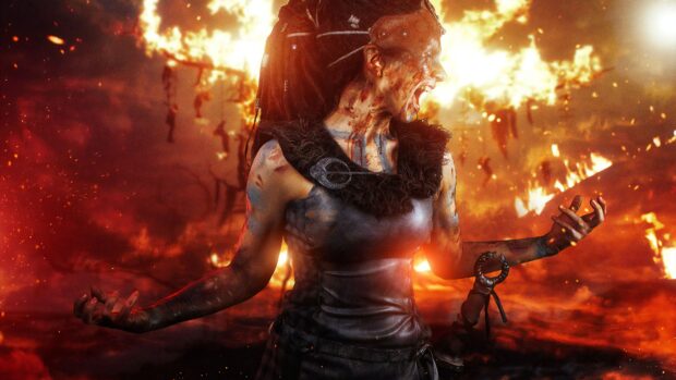A fierce warrior covered in war paint and battle scars shouts with flames erupting behind her in Hellblade Wallpapers