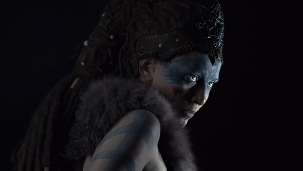 A close up of a Hellblade character wearing war paint and a fur cloak in the dark, 4K Desktop Wallpaper