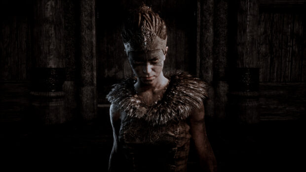 A fierce warrior from Hellblade stands in a dark ancient hall wearing fur and war paint, 4K Desktop Wallpaper