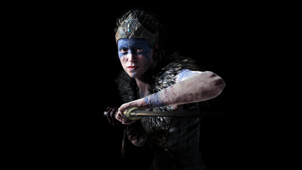 A fierce Hellblade character with blue face paint holding a sword in battle stance, 2K Desktop Wallpaper