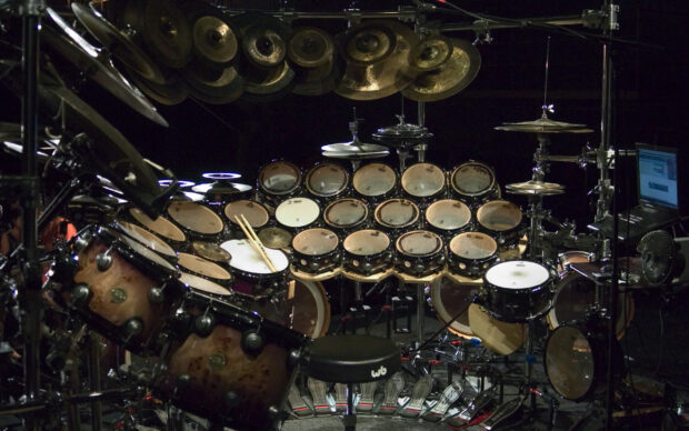 A highly detailed drum set with multiple drums and cymbals arranged on a stage with drumsticks resting on the drum, 2K Desktop Wallpaper