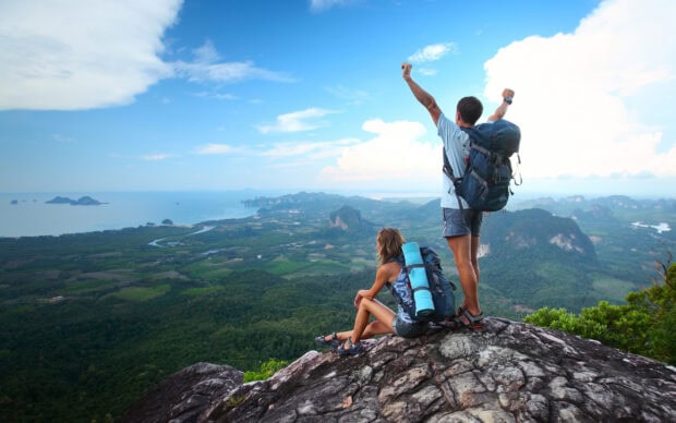 Two hikers enjoying the mountain view with backpacks after a long hiking trip