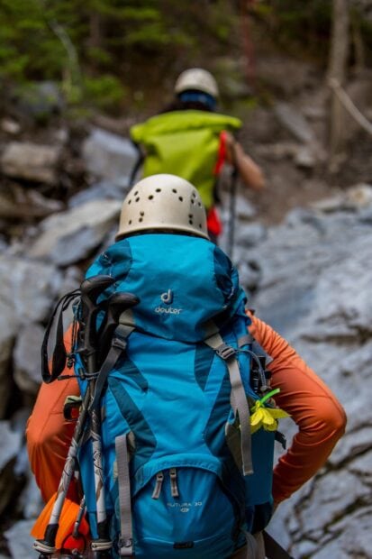 Hiker with a blue backpack climbing a rocky trail during a hiking adventure