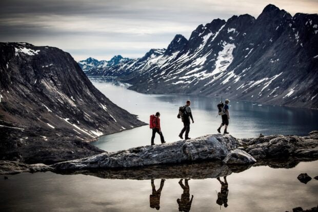 Three hikers explore rocky terrain near a mountain lake during a hiking adventure