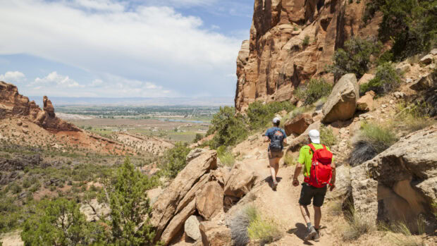 Two hikers walking on rocky hiking trail in desert canyon landscape