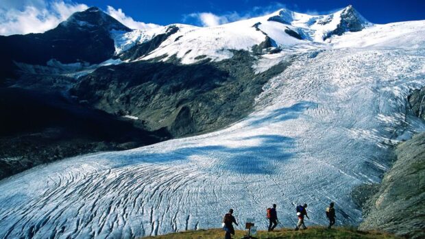 A mountain glacier with hikers trekking across a rugged landscape in nature