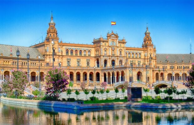 The historic Spanish building is reflected in the water on a sunny day, 2K Desktop Wallpaper