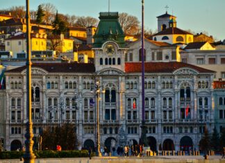The historic architecture of Trieste shines warmly at sunset with people walking nearby, 2K Desktop Wallpaper