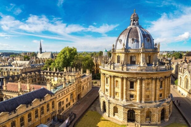 The image shows the historic architecture of Oxford University under a blue sky, 2K Desktop Wallpaper