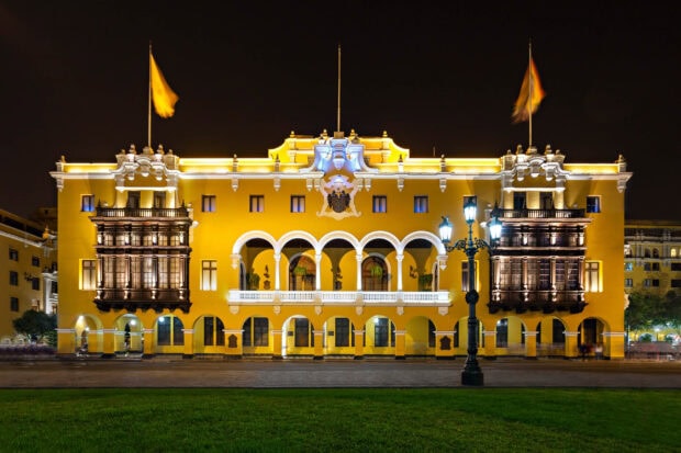 A historic building glows in bright yellow light in Lima Peru at night, 2K Desktop Wallpaper