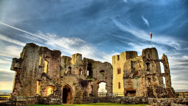 The ruins of a historic castle stand prominently under a partly cloudy blue sky in Wales, HD Desktop Wallpaper
