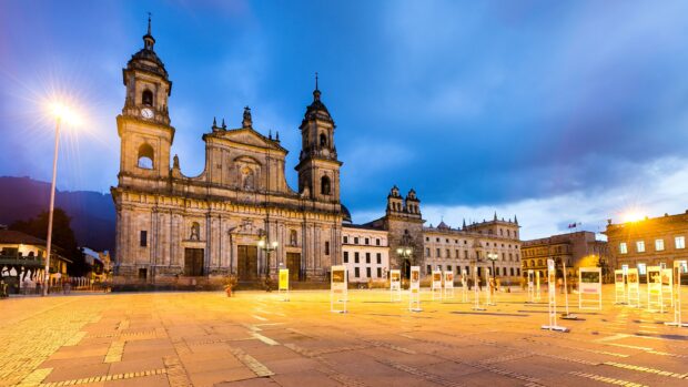 The historic cathedral stands tall in the main square of Bogota with illuminated street lamps during sunset