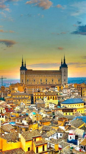 A stunning view of the historic cityscape in Spain with colorful buildings and a large castle under a sunset sky, HD Android Wallpaper