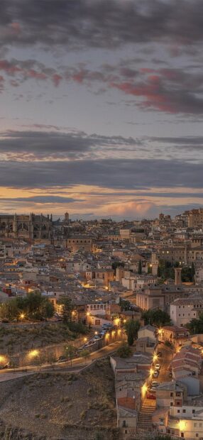 The Spain cityscape shows intricate buildings and warm sunset lights under a colorful sky, HD Mobile Wallpaper