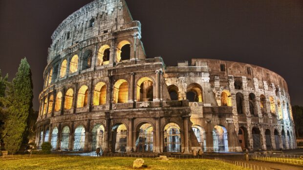Ancient Roman architecture stands illuminated at night in the Colosseum arena
