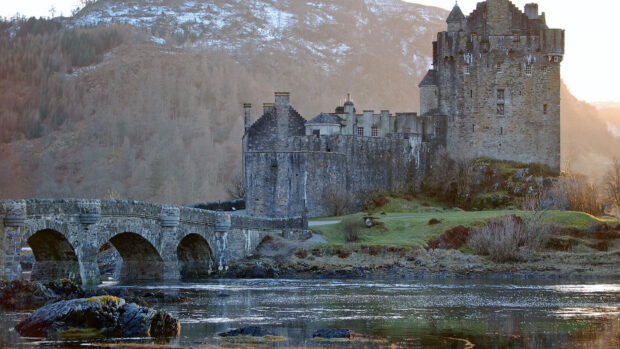 Ancient stone castle with historic architecture near river and stone bridge