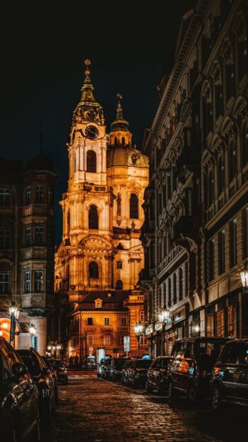 Historic city street with illuminated clock tower at night