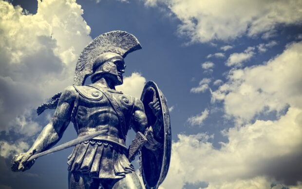 Ancient warrior statue stands proudly under cloudy sky with historical armor