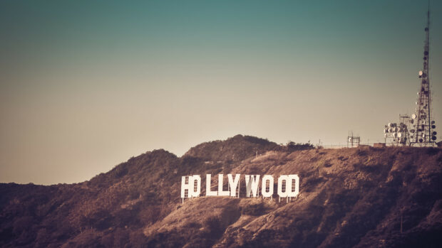The Hollywood sign on a hillside with a clear sky and communication towers in the background