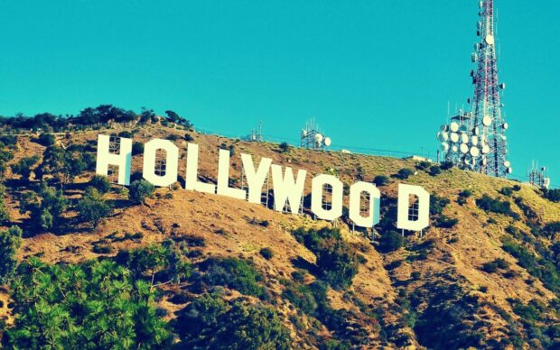 The famous Hollywood Sign on the hillside surrounded by dry vegetation and communication towers