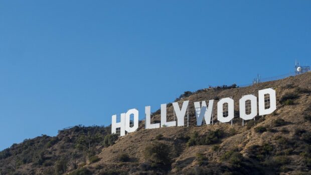 The iconic Hollywood Sign is visible on the hillside in clear blue sky with natural landscape