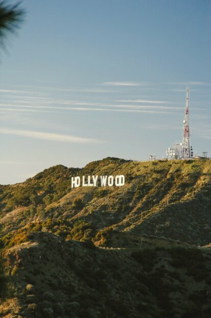 The iconic Hollywood sign on a hill surrounded by green vegetation and clear sky