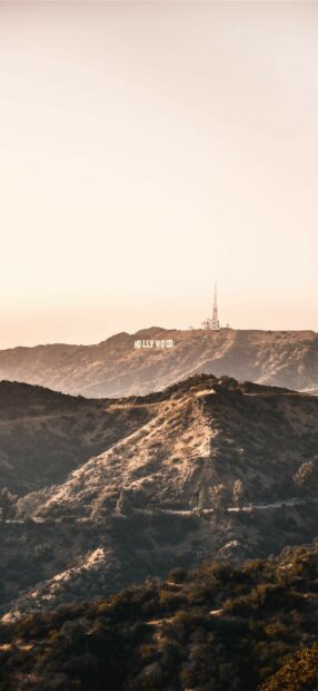 A scenic view of the Hollywood sign on hills during golden hour with clear sky