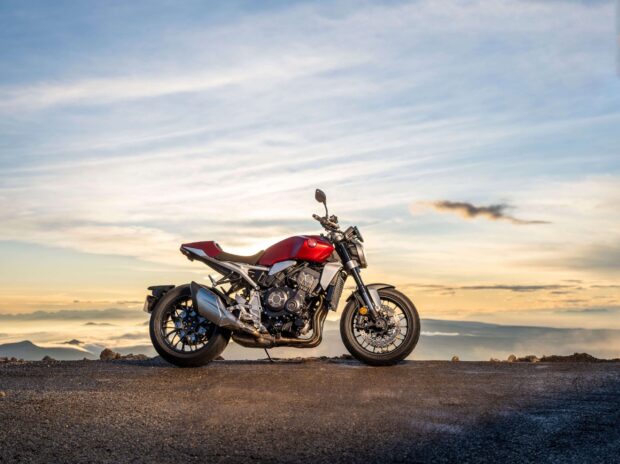 A red Honda CB1000R stands on a gravel road under a colorful sky, 2K Desktop Wallpaper