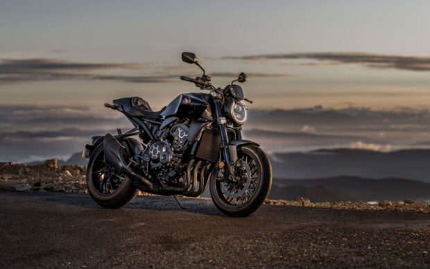 A black Honda CB1000R motorcycle parked on a road with a cloudy sky background, 2K Desktop Wallpaper