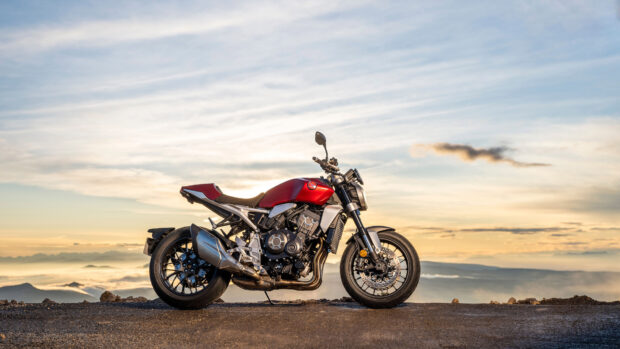 A red Honda CB1000R motorcycle is parked on a mountain road during sunset with a cloudy sky, 4K Desktop Wallpaper