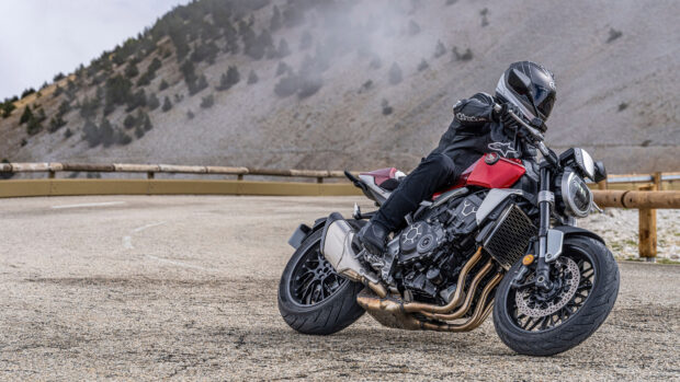 A rider leans into a curve on a red Honda Cb1000R motorcycle on a mountain road, 4K Desktop Wallpaper
