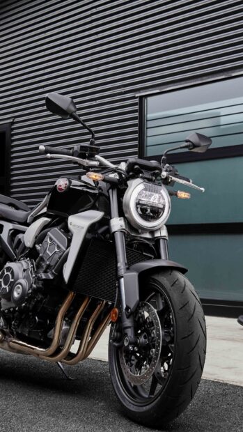 A close up of a Honda Cb1000R motorcycle parked near a building with metal siding, 2K Phone Wallpaper
