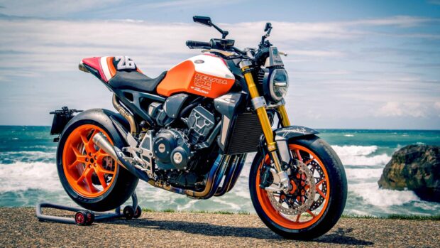 A Honda Cb1000R features bright orange accents parked near a rocky shoreline, 2K Desktop Wallpaper