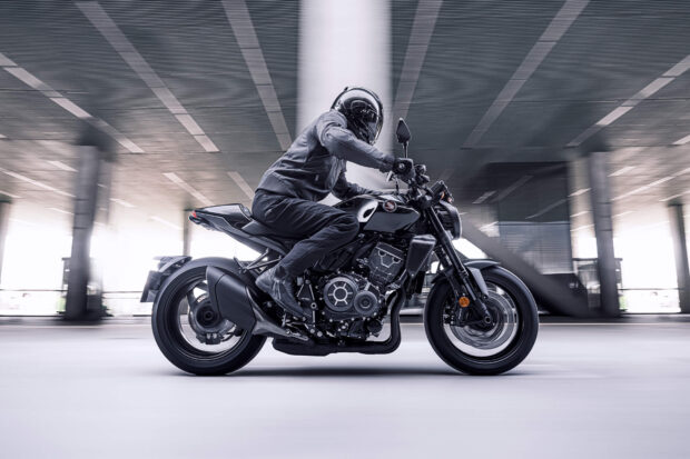 A rider is on a black Honda Cb1000R motorcycle in a modern city setting, HD Desktop Wallpaper