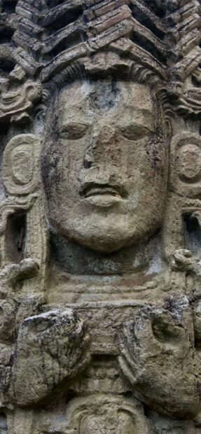 Ancient Honduras sculpture carved in stone showing intricate facial details and hands gesture