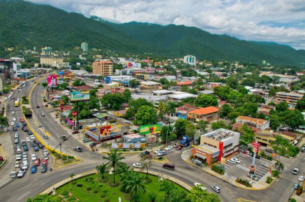 Aerial view of Honduras city with green mountains and urban streets in clear weather
