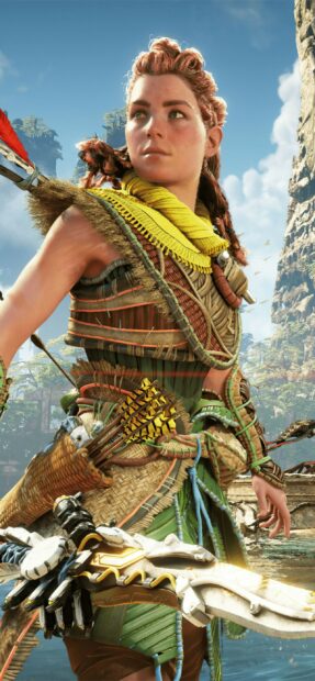 Aloy from Horizon Forbidden West stands ready with her bow in a lush outdoor setting