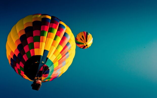 Colorful hot air balloon floating in the clear blue sky with another balloon in the distance