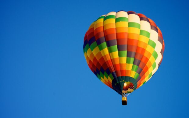 A colorful hot air balloon floating against a clear blue sky