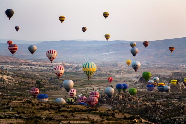 Colorful hot air balloon flying over the vast landscape with mountains and fields