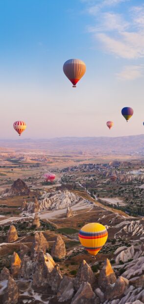 Colorful hot air balloon floating over rocky landscape at sunrise