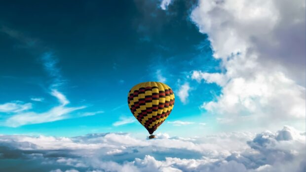 A colorful hot air balloon floating above clouds under a vibrant blue sky
